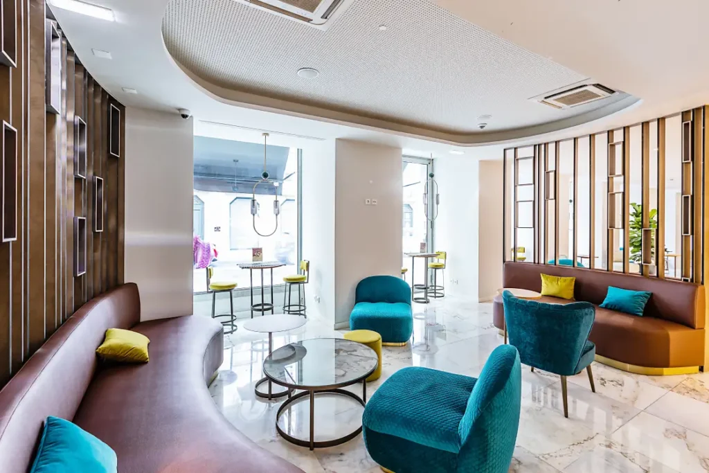 Aménagement d’un espace lounge : mobilier sur mesure, palette bleu canard et jaune, marbre et claustra en bois